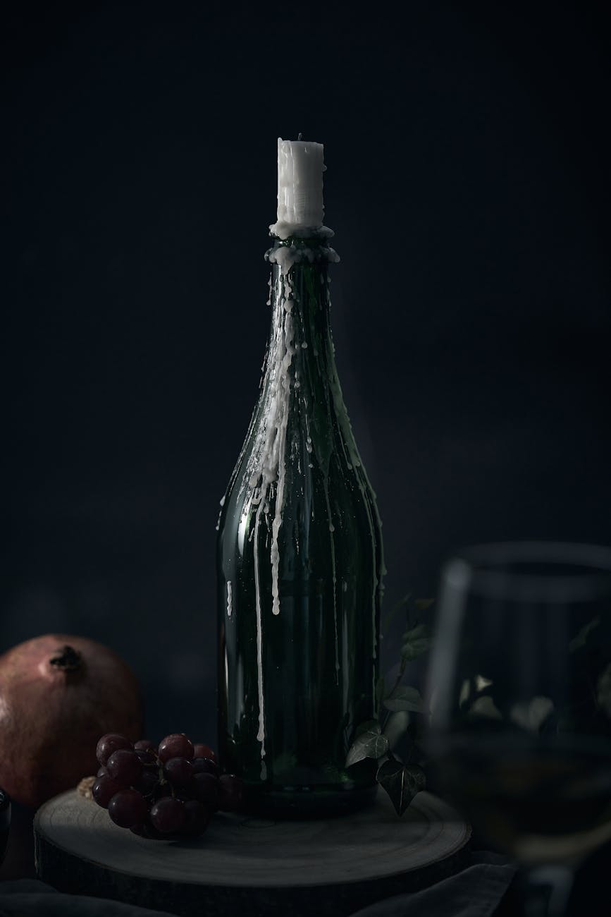Bodegón oscuro con frasco cubierto de cera y velas