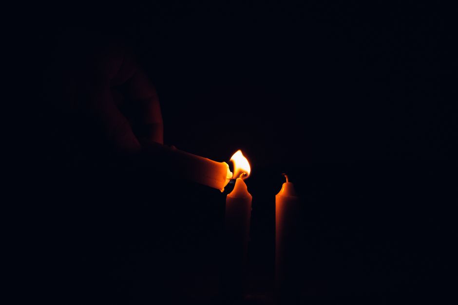 Mano encendiendo velas en una escena oscura del taller