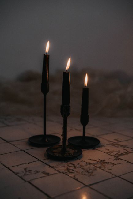 Tres velas negras encendidas en un ambiente sombrío